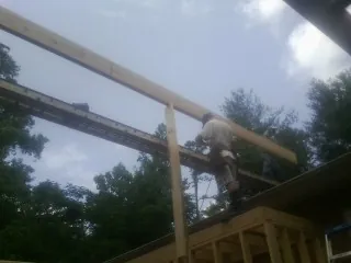 Carpenter setting a ridge beam over a new addition frame in Kite