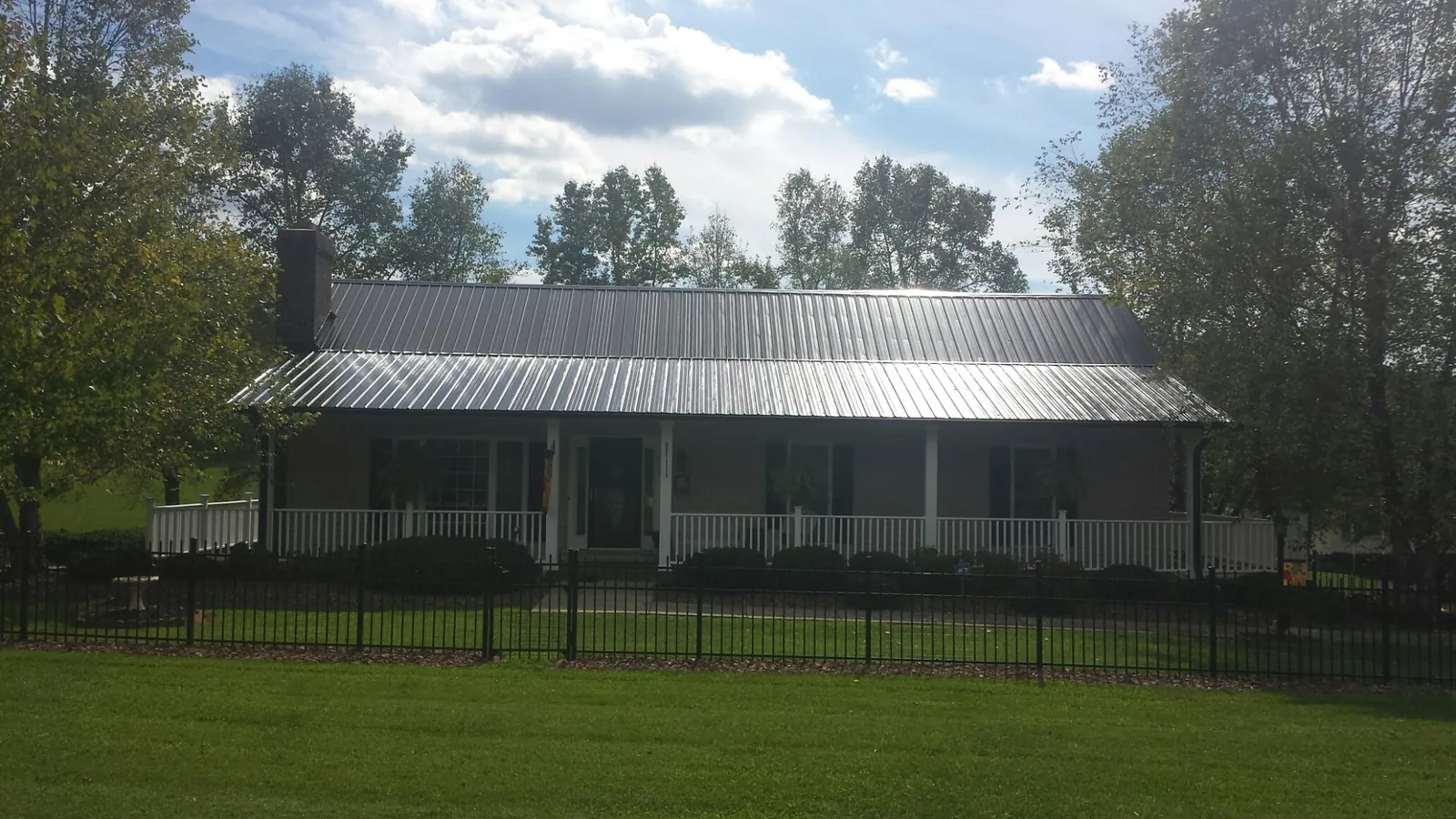 Gray metal roof on a brick ranch with a full width front porch — Gutter Guard Installation work by our crew in Kite
