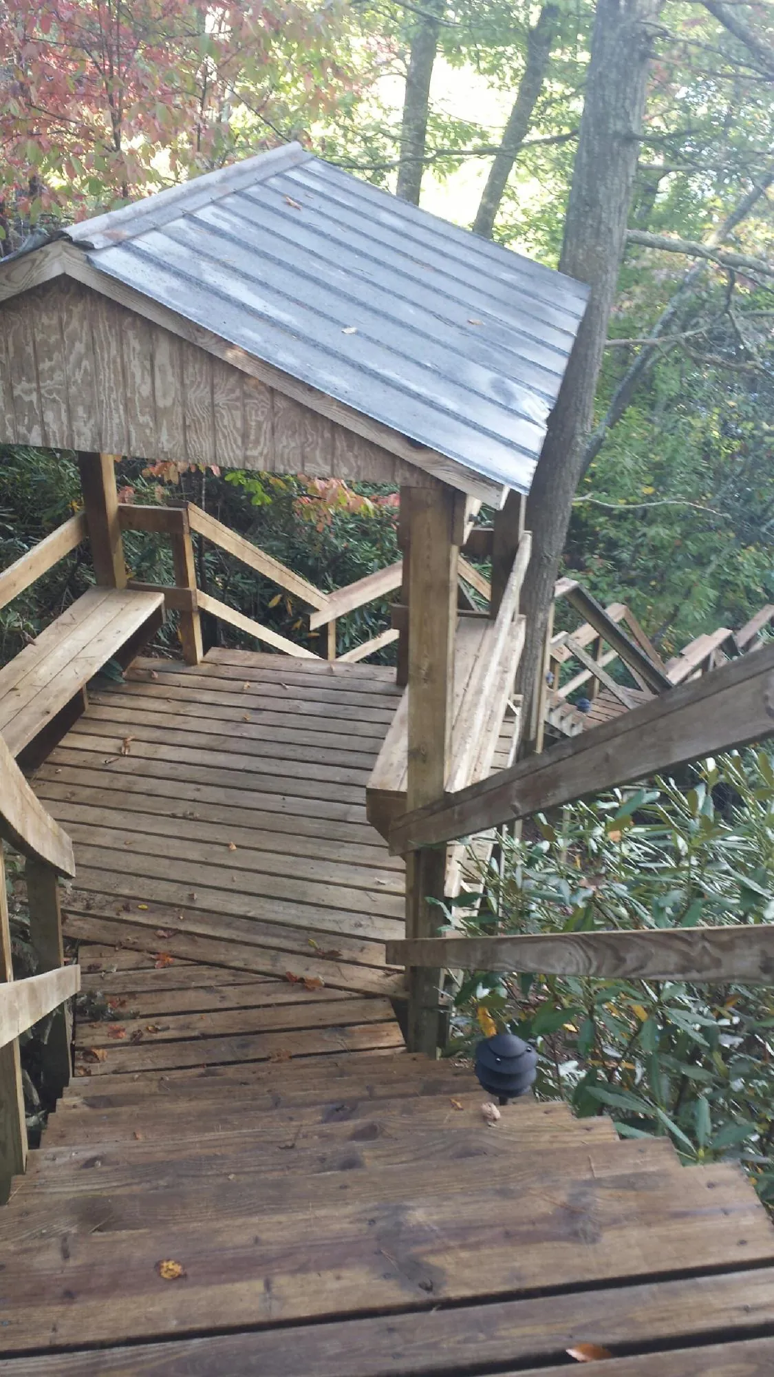 Metal roofed shelter over wooden steps on a wooded walkway — Skylight Repair & Installation work by our crew in Kite