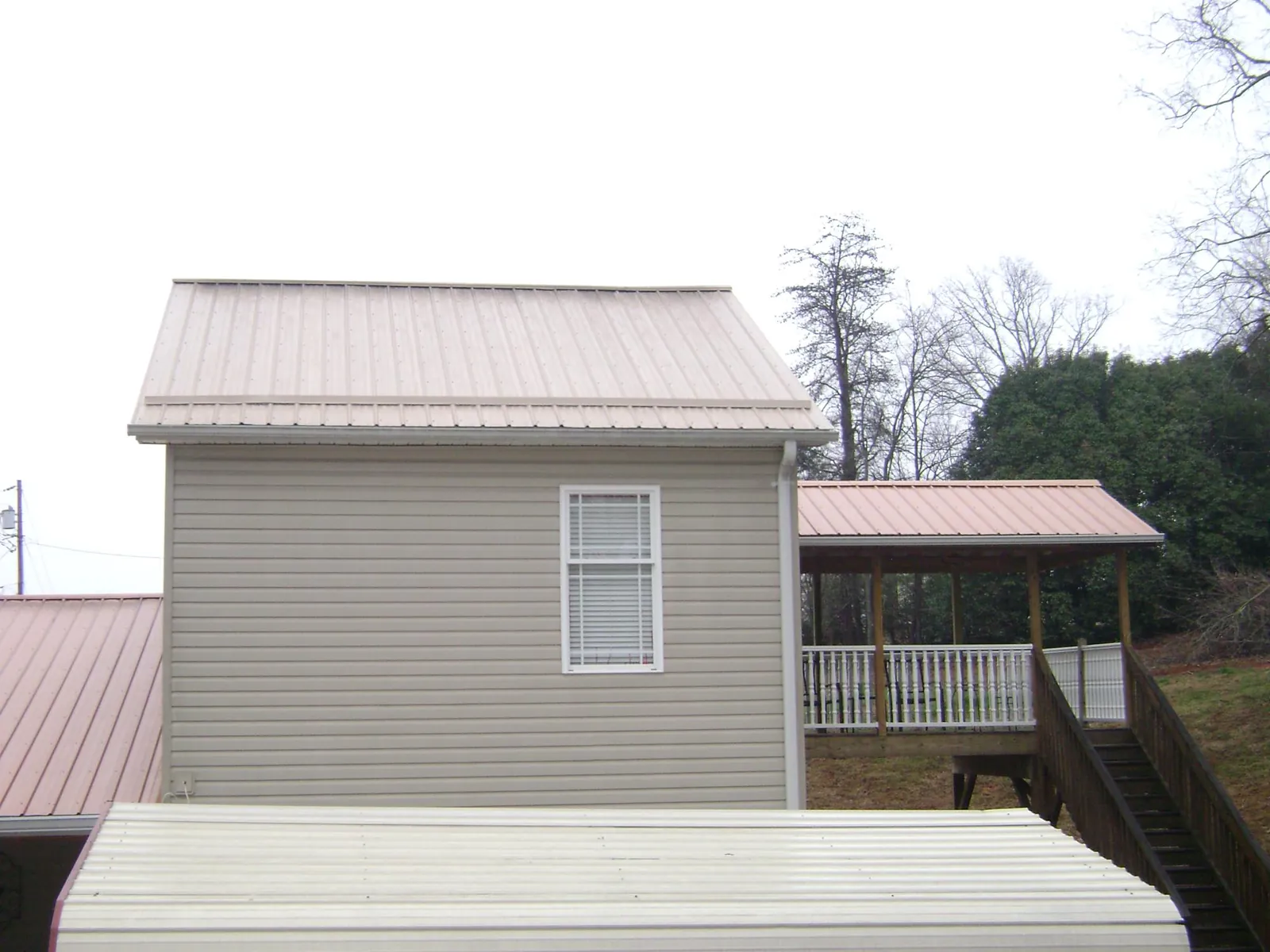 Tan metal roofs on a two story addition and attached porch, from a Roof Replacement job in Kite